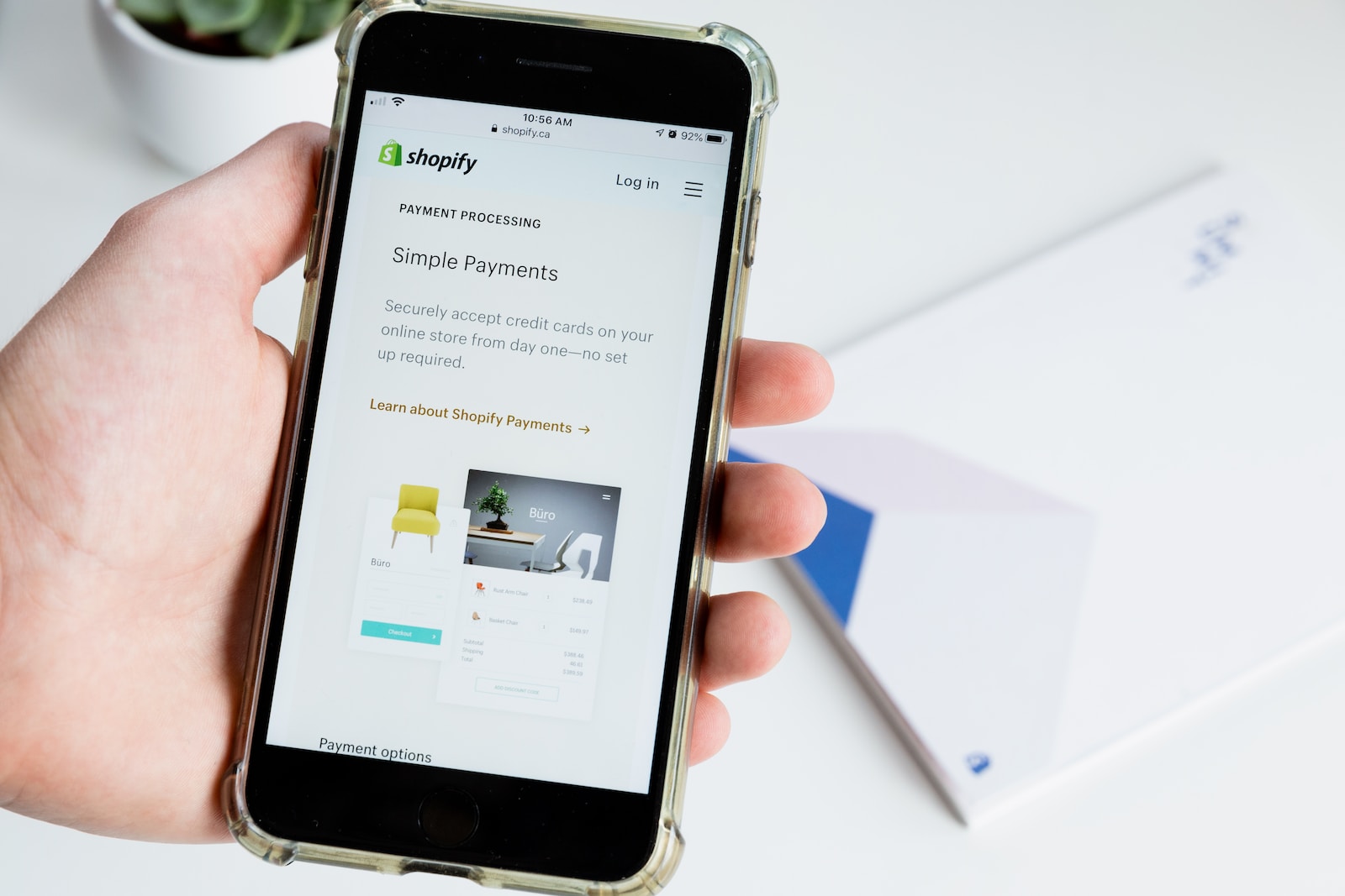 Une personne tient un téléphone sur lequel est installée une application Shopify.