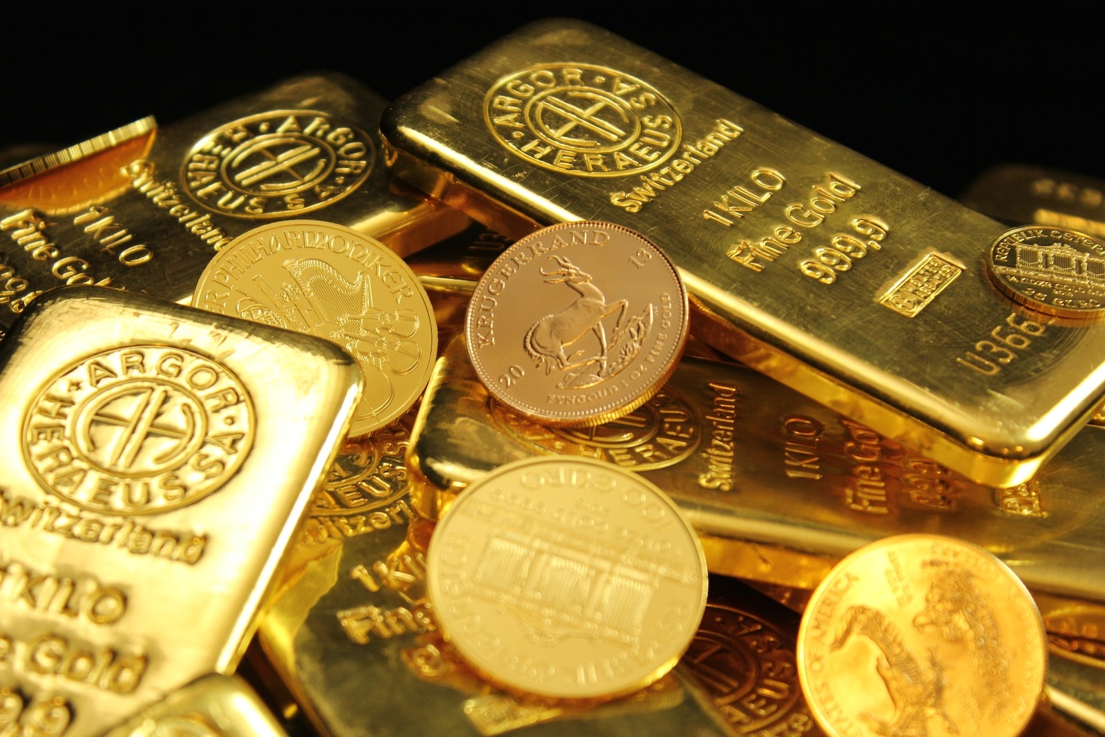 Une pile de lingots d'or et de pièces de monnaie sur fond noir.
