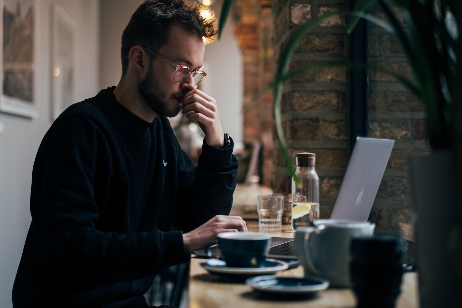 Un homme assis à une table avec un ordinateur portable et une tasse de café.