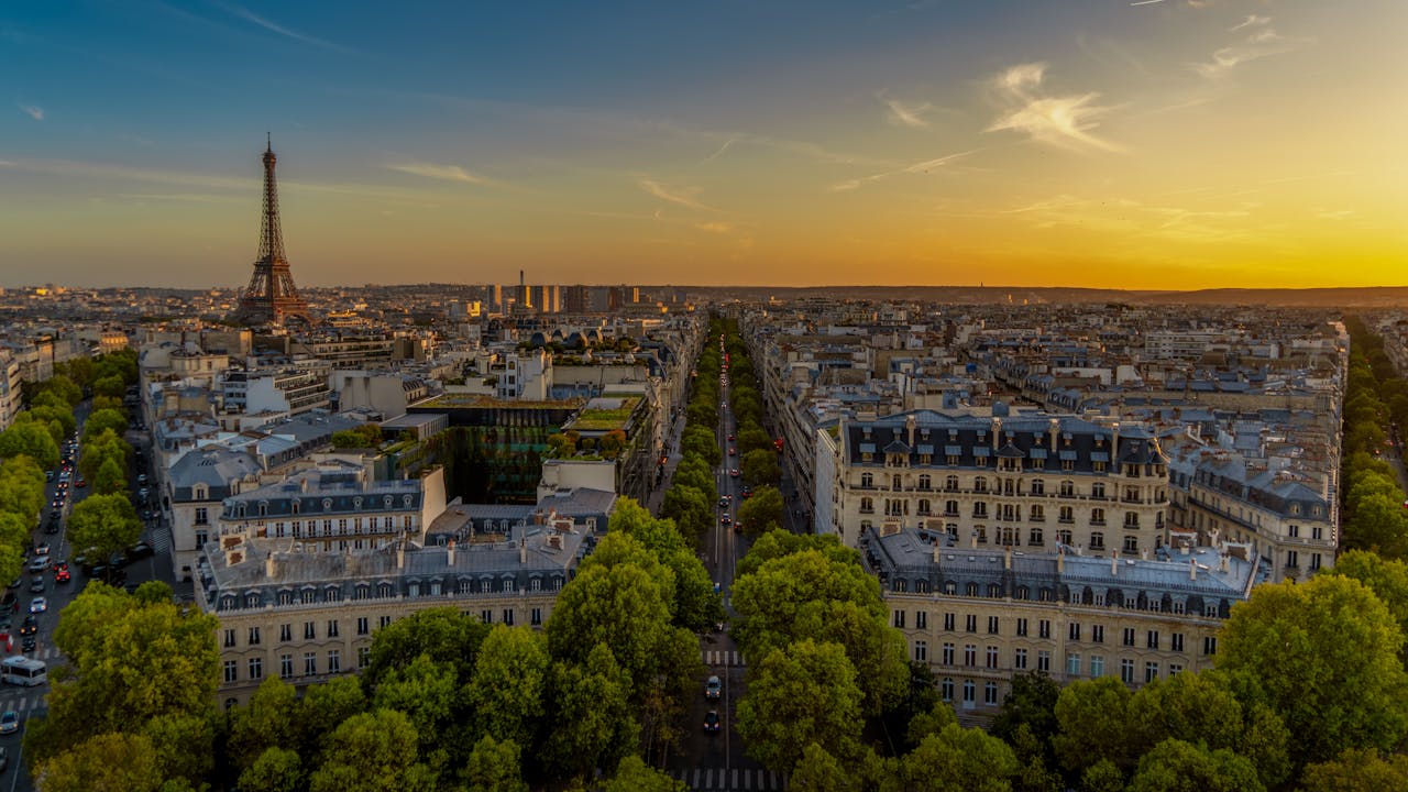Vue aérienne de Paris au coucher du soleil avec la tour eiffel en arrière-plan.