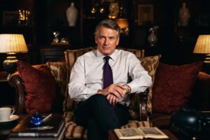 Homme en costume blanc assis dans un fauteuil luxueux