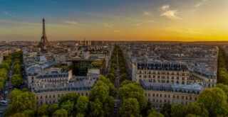 Vue aérienne de Paris au coucher du soleil avec la tour eiffel en arrière-plan.